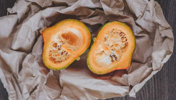 Una fruta abierta de color naranja siobre un papel arrugado marrón.