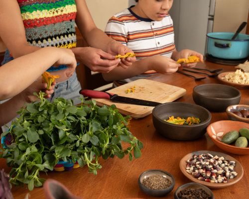 Una familia cocinando en una mesa de madera de forma conjunta.